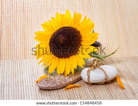 Spa background with natural soap, bath salts, and sunflower.