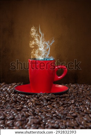 Red cup of coffee with steam on a background of coffee beans.