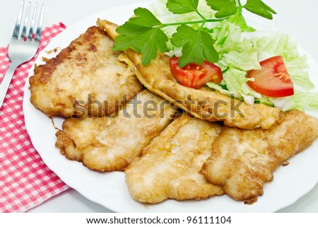 Fried fish fillets with egg and salad.