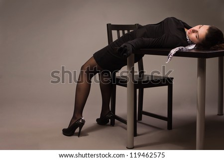 Detective scene imitation. Woman in a black suit lying on a table