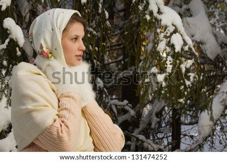 Russian beautiful girl in a traditional dress in the winter forest