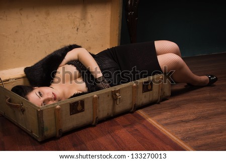 Crime scene in a vintage style. Pretty victim lying in the suit-case