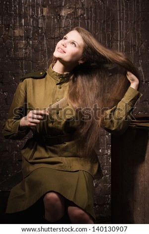Soviet female soldier in uniform of World War II combs her hair