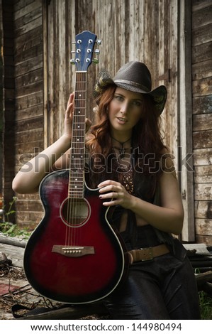 Pretty country girl with guitar on the ranch