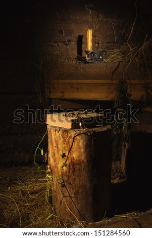 Old book and candle in a dark village interior