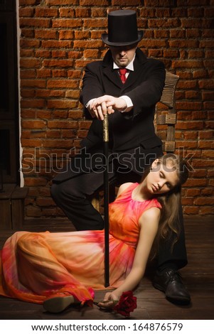 Man in the black coat, top hat and in a red tie and beautiful girl with rose