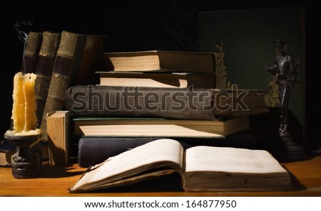Vintage still life. Old books and candles on wooden table on dark background
