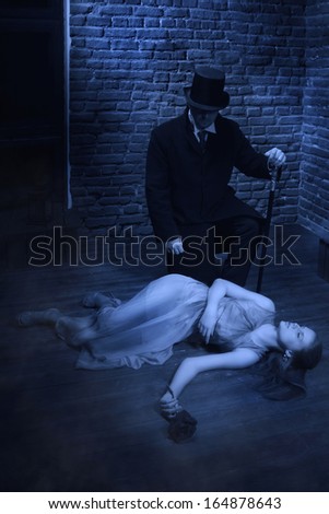 Vampire and his victim. Man in the black coat, top hat and in a red tie and beautiful girl with rose
