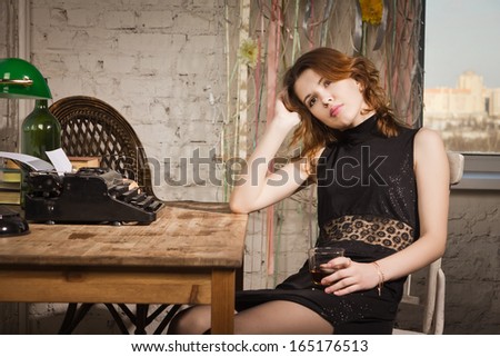 Elegant woman in black at the table with the old typewriter