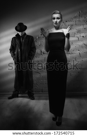 Film noir. Woman in a long black dress and a man in a raincoat and hat