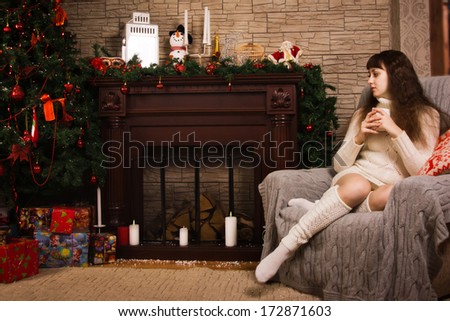 Young girl posing by the fireplace with Christmas gifts