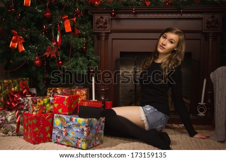 Young girl posing by the fireplace with Christmas gifts