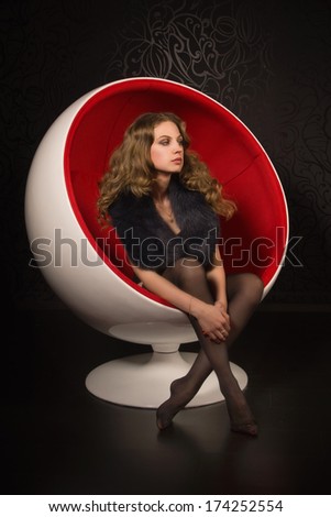 Attractive woman in sexy lingerie sitting in a red ball-chair