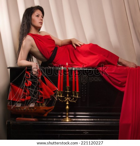 Fashionable brunette in a long red dress in the vintage interior