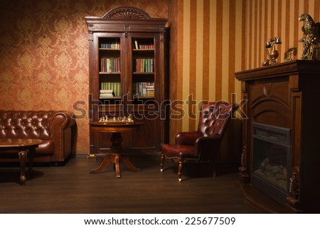 Classical library room with leather armchair, wooden table and bookcase