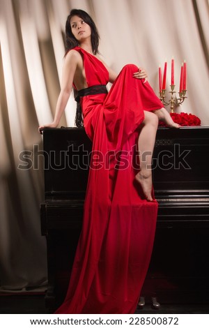 Fashionable brunette in a long red dress in the vintage interior