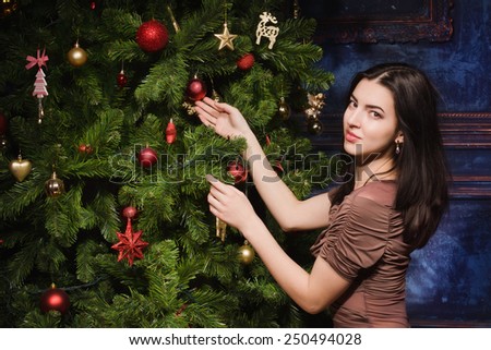Beautiful young girl near a Christmas tree with gifts