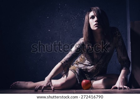 Asylum. Lonely mad woman with red apple sitting on a floor. Low key.