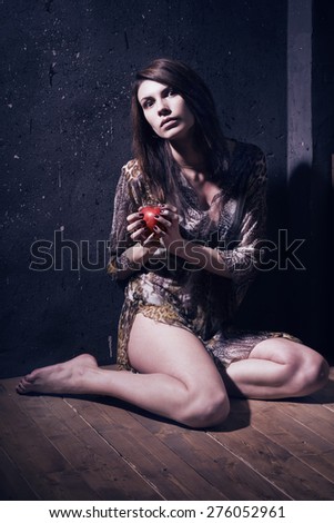 Asylum. Lonely mad woman with red apple sitting on a floor. Low key.