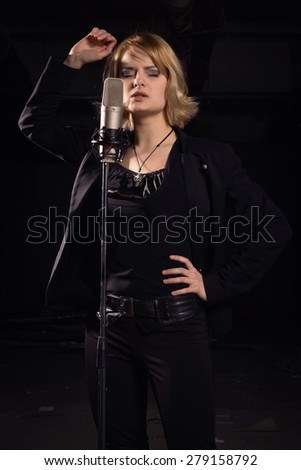 Rock star singing into a microphone on industrial background. Low key, tonal correction