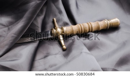 Raincoat and dagger. The ancient dagger is covered by a black raincoat