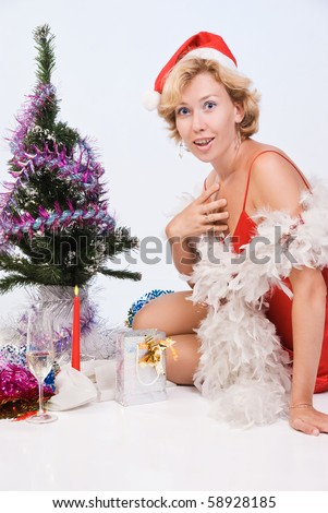 Beautiful woman wearing santa claus clothes looks in a gift package