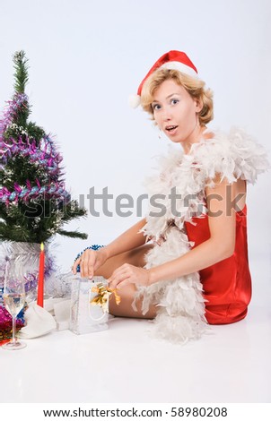 Beautiful woman wearing santa claus clothes looks in a gift package