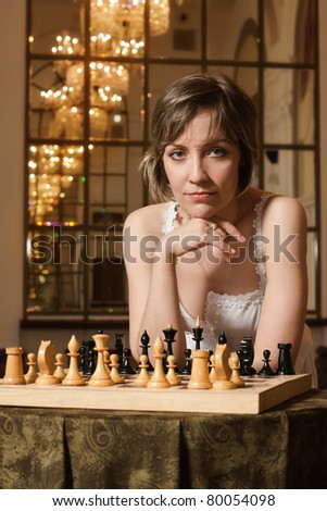 Young  blond woman play chess in the rich interior