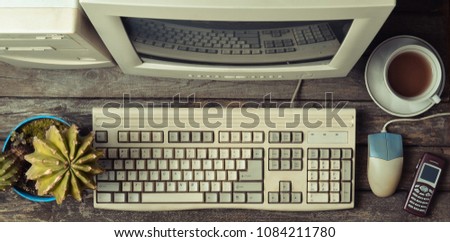 Retro stationary computer on a rustic wooden desk, vintage workspace. Monitor, keyboard, computer mouse, top view, flat lay