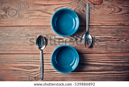 Ceramic bowls for baking and spoons . Kitchen composition. Cutlery and table utensils. The process of cooking. Wooden background.