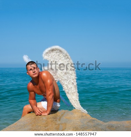 Muscular man with angel wings on the beach