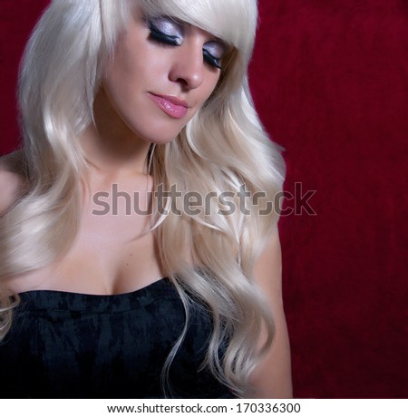 Portrait Luxury glamorous blonde with long wavy hair on a red background barhotnom