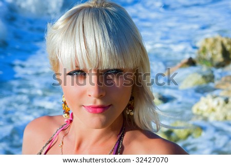 The beautiful blonde the girl with bright blue eyes against the dark blue sea