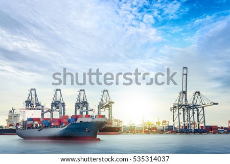 Logistics and transportation of international container cargo ship with ports crane bridge in harbor at dusk for logistics import export background and transport industry