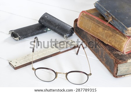 Old glasses and pile of vintage books and old slide-rule