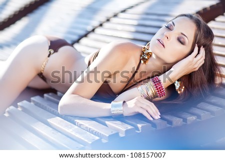 Woman sunbathing in bikini at tropical travel resort. Beautiful young woman lying on sun lounger.