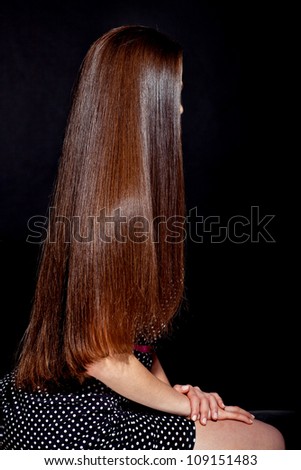 closeup portrait of a beautiful young woman with elegant long shiny hair from back , hairstyle , on a black background , healthy straight hair