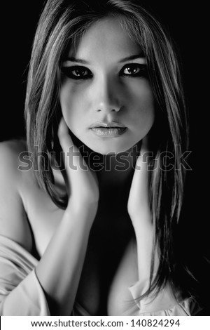 Fashion photo of a beautiful woman on a black studio background. Black and white.