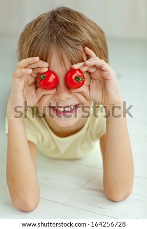 Portrait of happy boy holding ripe tomatoes before his eyes