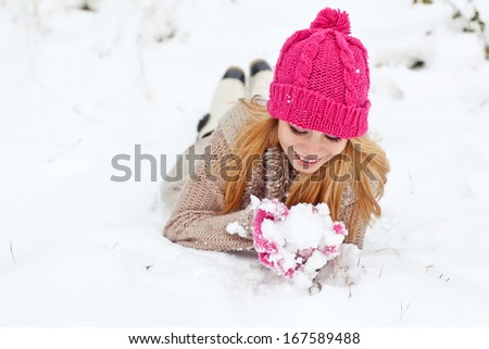 Winter woman in snow looking at camera outside on snowing cold winter day. Portrait  female model outside in first snow