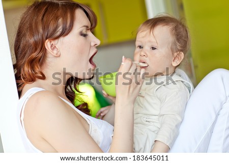Mother feeding her baby with a spoon. Mother giving food to her adorable baby at home