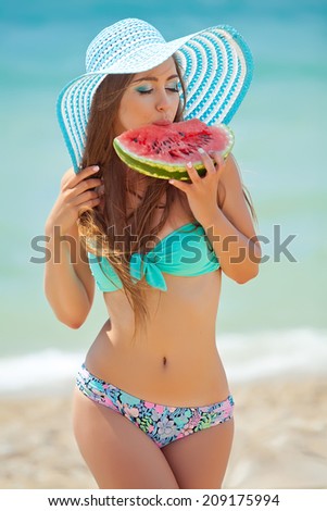 Young stylish lady in a hat at sea with watermelon