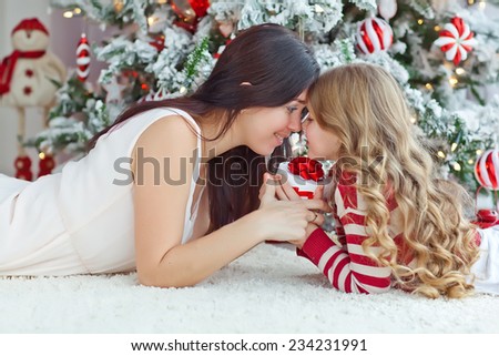 christmas, holidays, people and family concept - smiling mother and daughter opening gift  and getting surprised at home