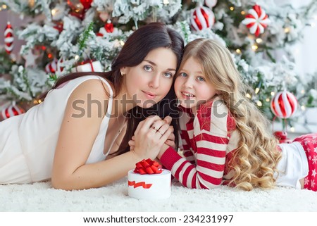 christmas, holidays, people and family concept - smiling mother and daughter opening gift  and getting surprised at home
