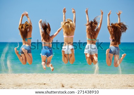 summer, vacation, holiday, happy people concept - a group of friends jumping and running on the beach