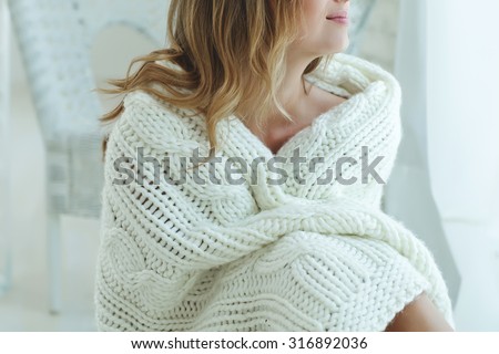 Young beautiful woman in warm knitted handmade clothes at home. Model fashion shooting. Autumn, winter season.