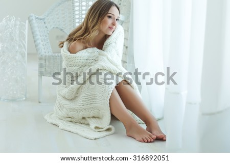 Young beautiful woman in warm knitted handmade clothes at home. Model fashion shooting. Autumn, winter season.