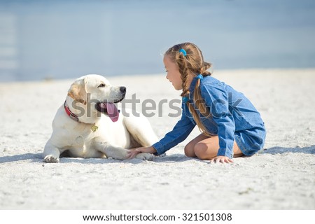 The girl with the dog on the shore of the sea. The child and a dog.