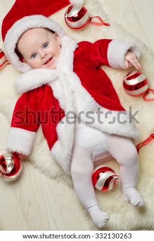 Beautiful little baby celebrates Christmas. New Year\'s holidays. Baby in a Christmas costume with gift