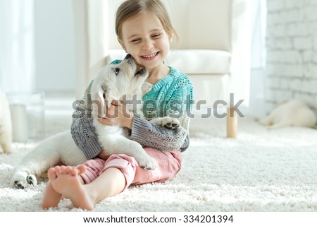 Portrait of happy little girl at home with labrador puppy